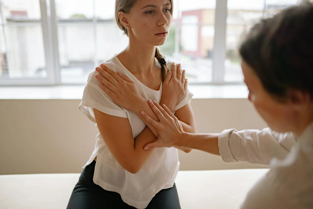Physical therapist guiding a patient through a shoulder rehabilitation exercise in a clinic setting, focusing on preventing sports injuries.